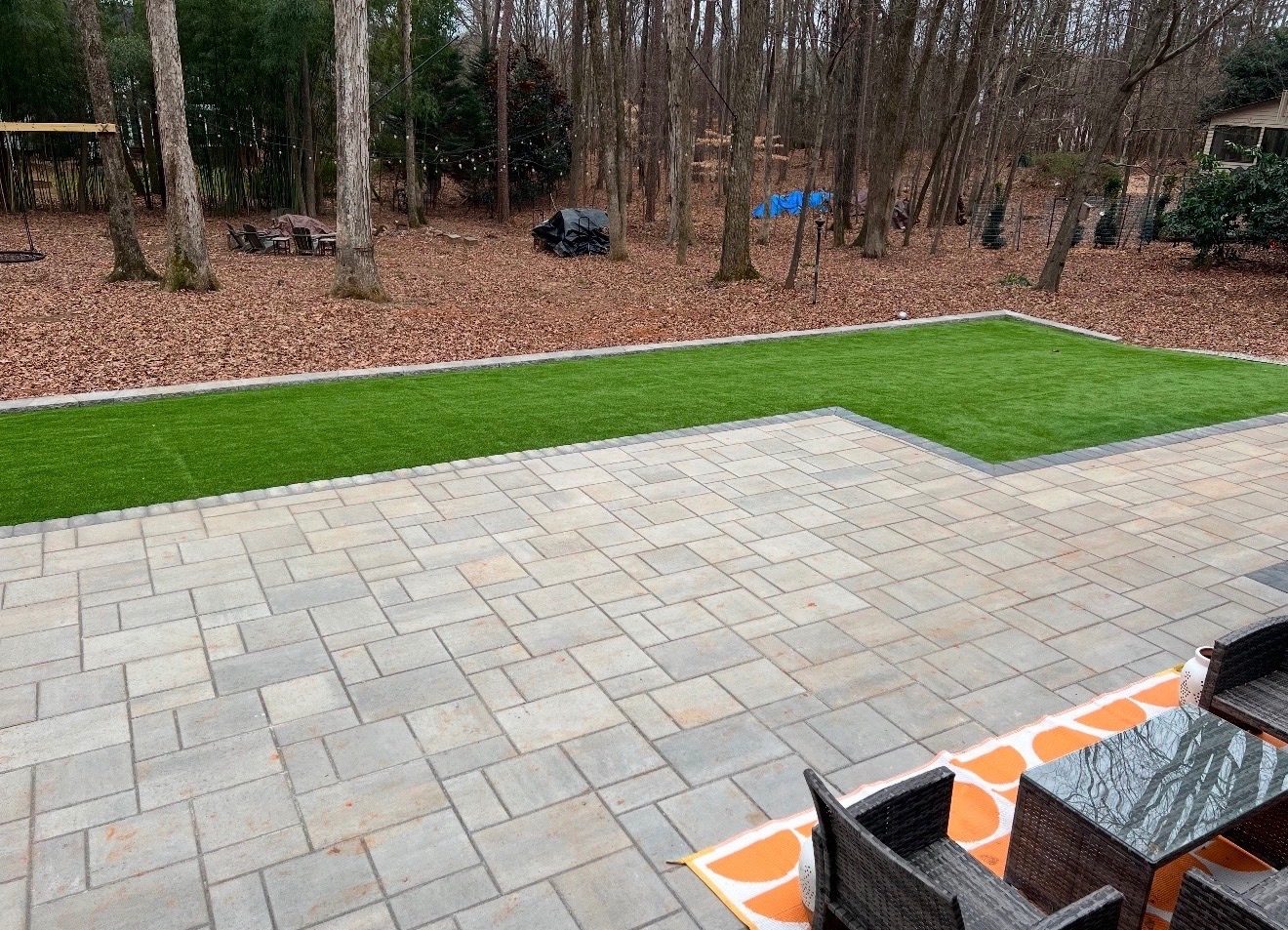 Large paver patio with artificial turf lawn by Andrew's Landscaping